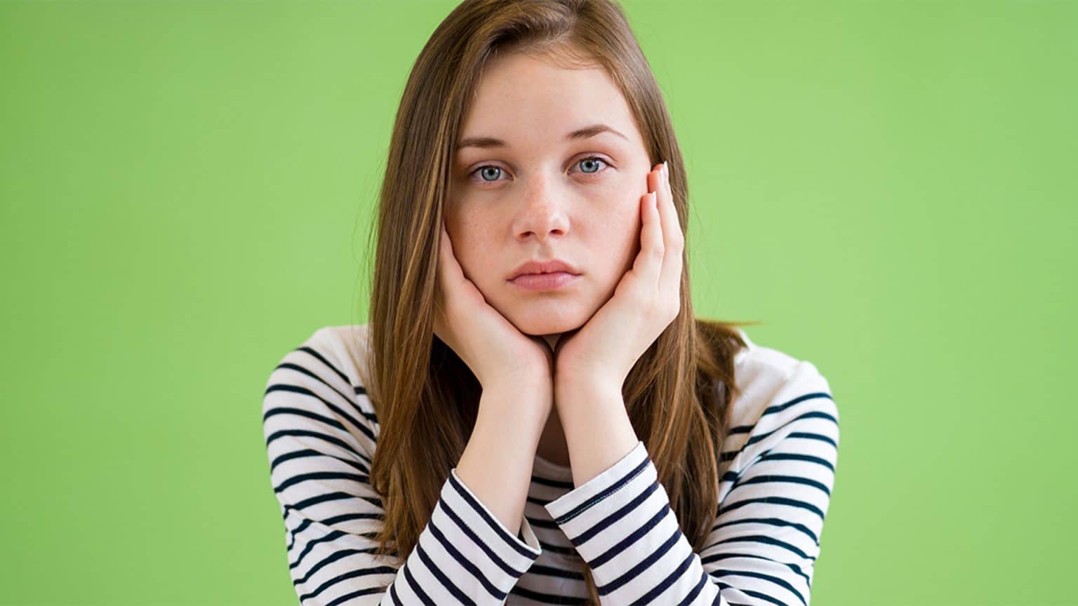 Sad student sitting in classroom with her head in hands.