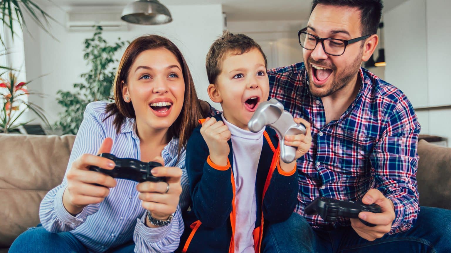 Happy family sitting on a sofa and playing video games.