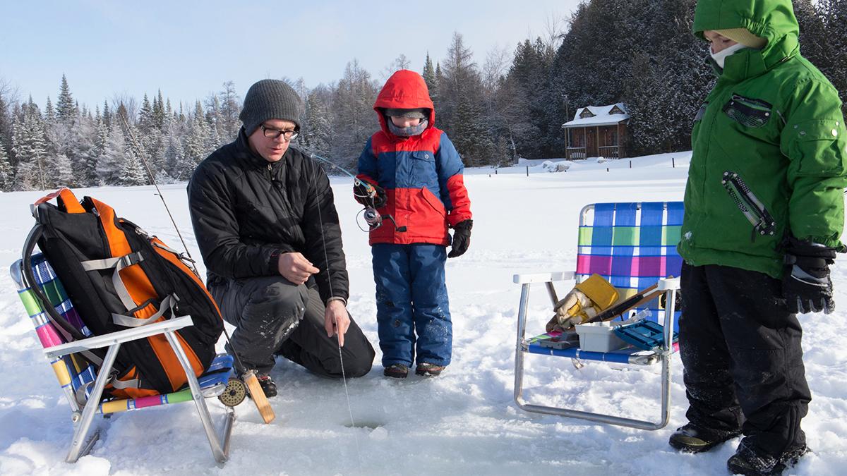Family ice fishing on the lake in Winter.