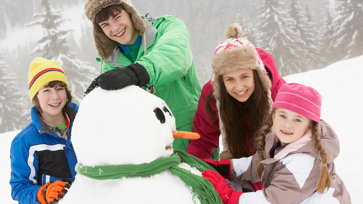 Group of children building snowman in Winter.